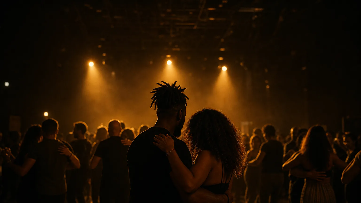 Dancers on a social floor at night, lit in warm gold from above