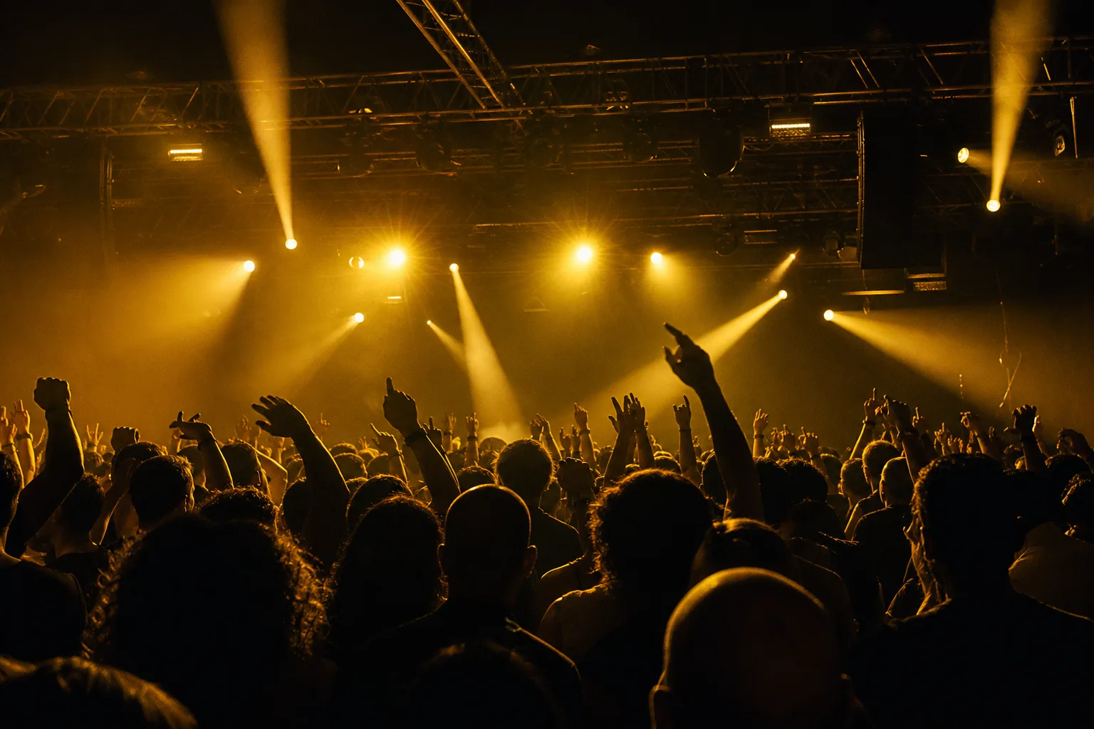 A packed festival room at night, gold beams cutting through haze above the crowd